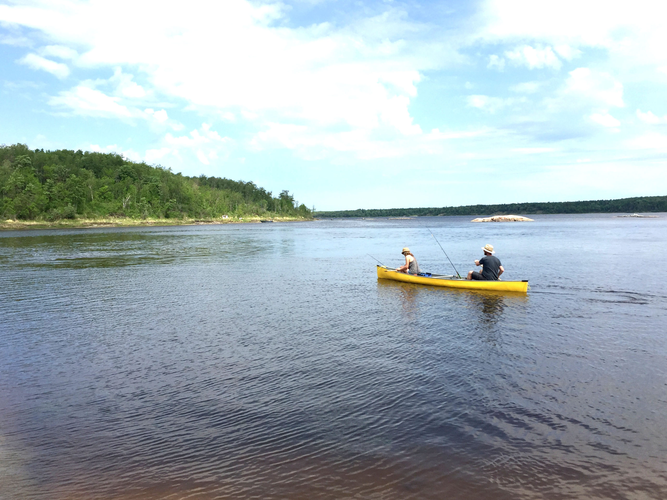Two people fishing in a yellow canoe