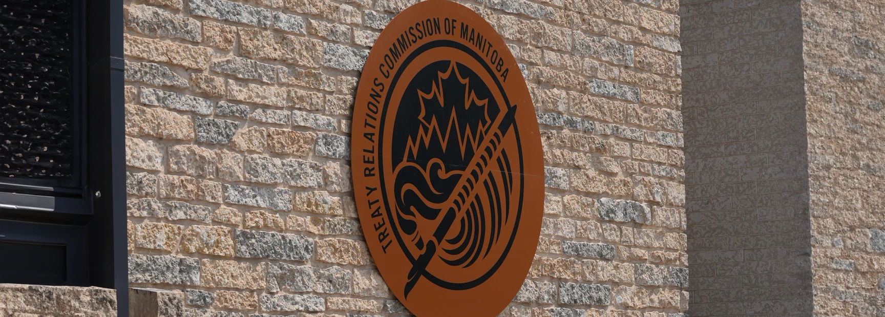 Treaty Relations Commission Of Manitoba logo outside of brick building.